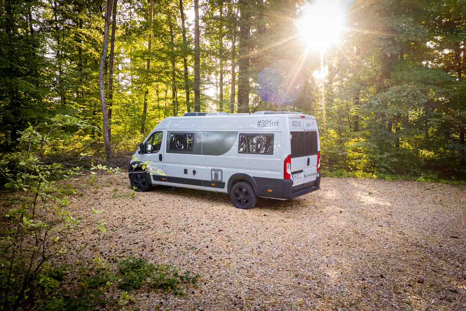 Pössl Summit 640 Wohnmobil im Wald mit strahlender Sonne